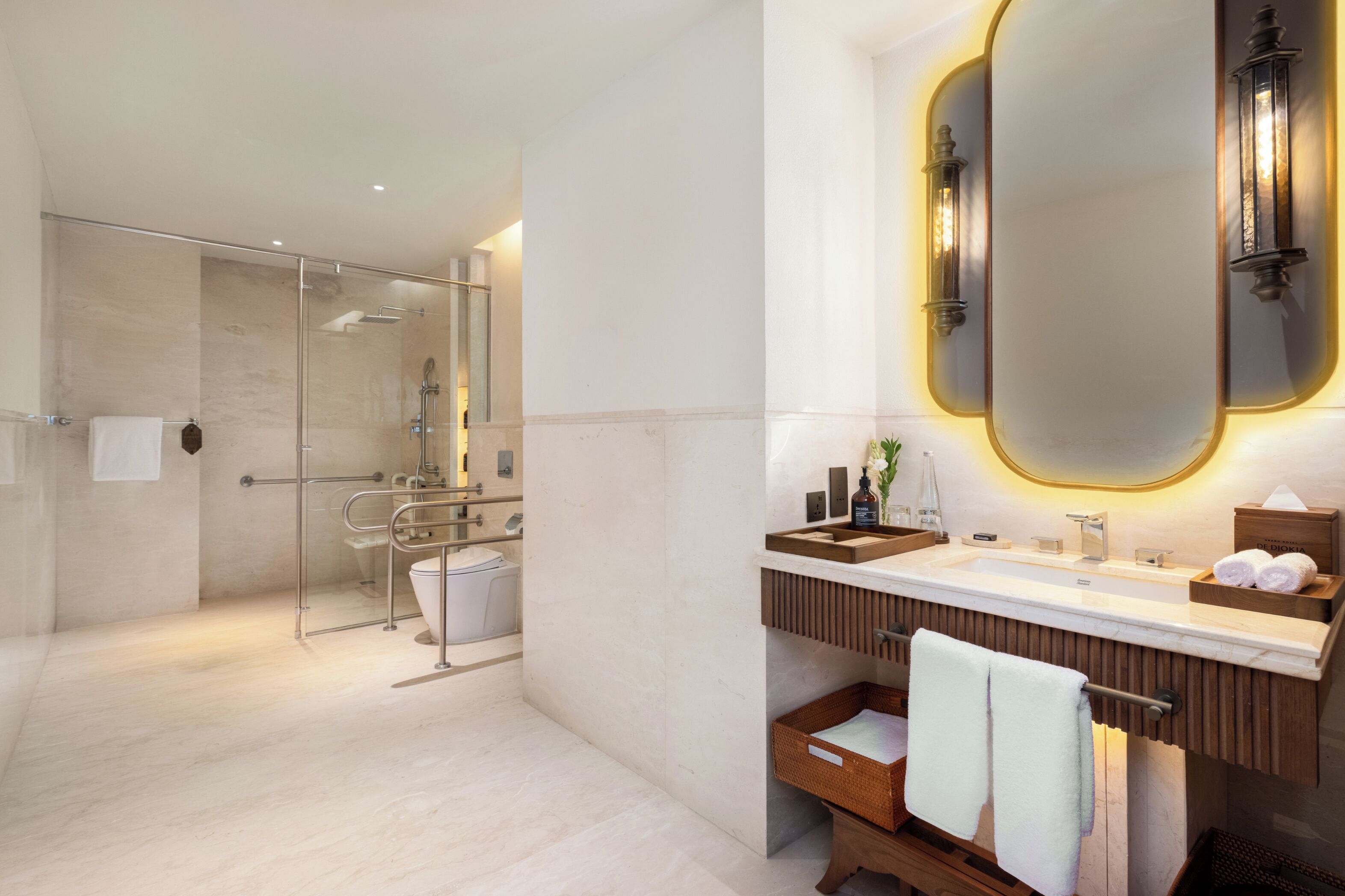 Un baño moderno con cabina de ducha de vidrio, tocador con espejo y banco de madera.