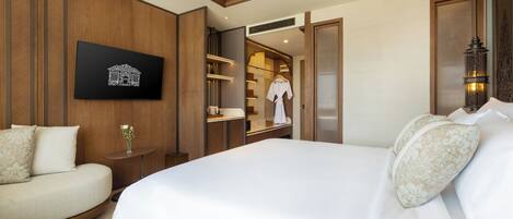 Habitación de hotel con una cama grande, un sofá, una mesita de noche con un florero y un armario con una bata.