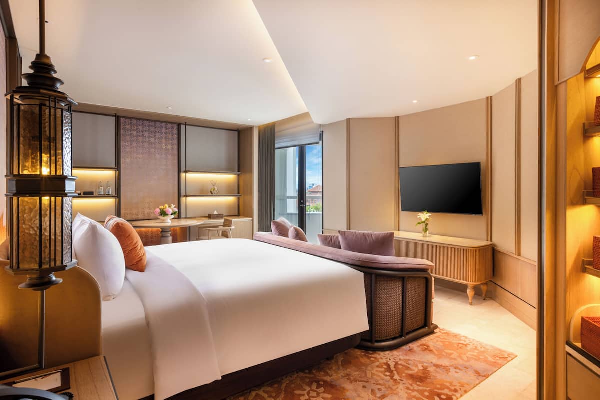 A modern hotel room with a large bed, a TV, a desk, and a view of the outdoors.