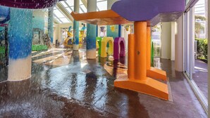 Un espace de jeux aquatiques intérieur, avec des structures colorées et un sol mouillé.