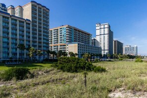 A hotel with multiple high-rise buildings, a grassy area in the foreground, and a clear blue sky.