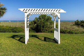 En hvid pergola med kig til havet i baggrunden.