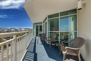 Un balcon donnant sur la rue, avec une balustrade et une table entourée de chaises.