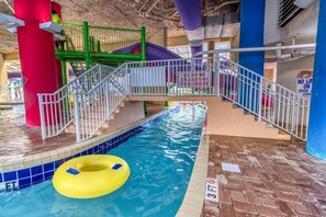 Une piscine intérieure avec un toboggan, un anneau gonflable jaune et un indicateur de profondeur indiquant 3 pieds.