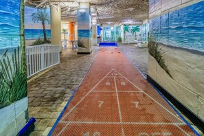 Un couloir agrémenté d’un terrain de jeu de « shuffleboard », de palmiers et d’une fresque représentant l’océan.