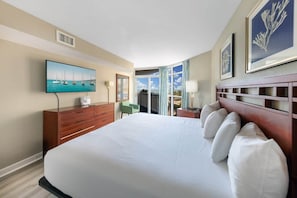 Una habitación de hotel con una cama grande, un televisor montado en la pared, un escritorio con lámpara y vistas al exterior a través de una ventana.