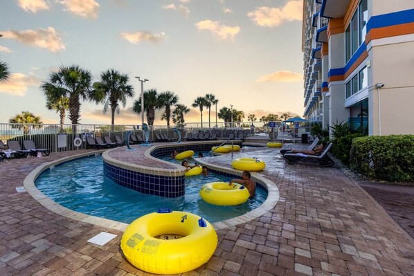 A swimming pool area with multiple lanes, lounge chairs, and yellow inflatable rings.