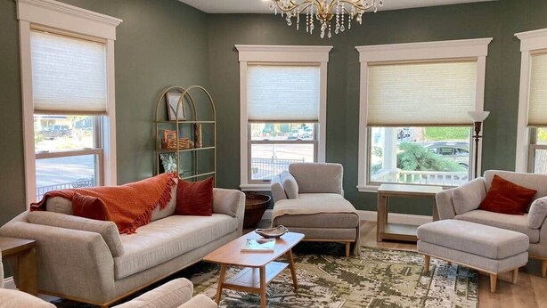A living room with a sofa, armchairs, a coffee table, and a chandelier.