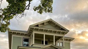 A two-story house with a front porch, a covered entryway, and a small front yard with potted plants.