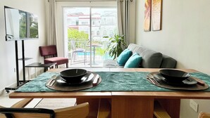 A dining area with a table set for two, a sofa with cushions, a chair, and a ceiling fan. - Local atmosphere great location 2 bedroom, Fast WiFi Ideal for long stays. (Cancún)