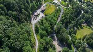 Vista aérea de una propiedad con un camino sinuoso, un bosque denso y algunos edificios.