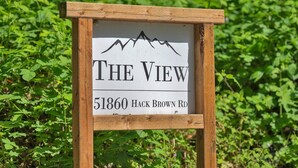A wooden sign with the text "THE VIEW" and "51860 HACK BROWN RD" indicating a property name and address.