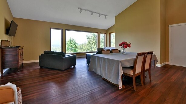 Una habitación amplia con una mesa de comedor, sillas, un sofá y un televisor sobre un aparador.