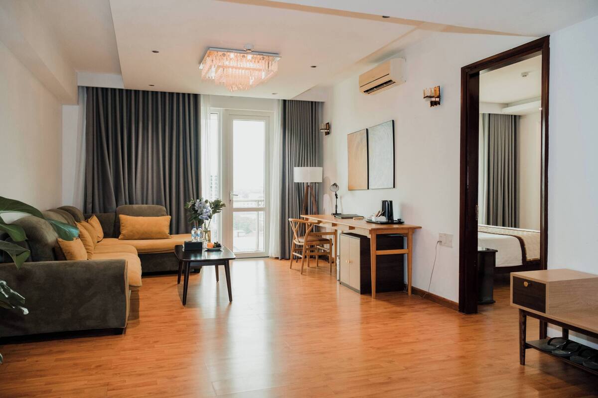 A modern living room with a sofa, a dining table, and a kitchen area.