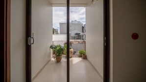 Uitzicht door een schuifdeur op een balkon met potplanten en een hekwerk.