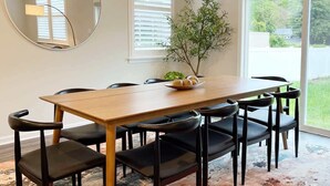 Ein Essbereich mit einem Holztisch, schwarzen Stühlen, einem runden Spiegel und einem Blumentopf.