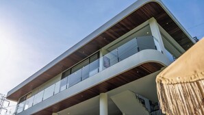A modern building with a curved facade, multiple balconies, and a wooden ceiling. - Jungle Breeze Villa by Betterplace (Cepaka)
