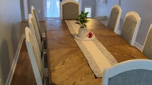 A dining room with a wooden table, white chairs, and a vase with flowers. - Spacious 3/2 Mt Dora home w/ Hot tub/Private in law suite & Lush fenced backyard (Mount Dora)