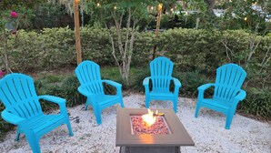 A fire pit table with four blue Adirondack chairs arranged around it. - Spacious 3/2 Mt Dora home w/ Hot tub/Private in law suite & Lush fenced backyard (Mount Dora)