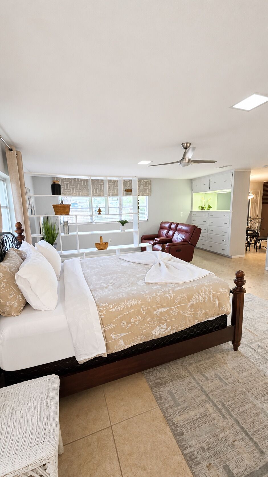 A bedroom with a large bed, a chair, a desk, and a ceiling fan.