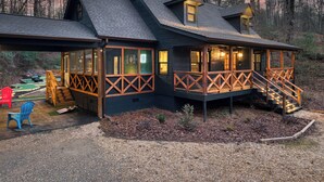 Une cabane dotée d’une terrasse, d’un porche couvert et d’un petit espace extérieur aménagé pour s’asseoir.