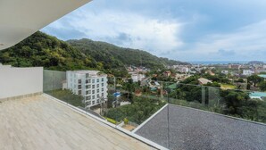 A balcony with a view of a hillside and a town below. - Sea View 2BR Condo Prime Location C236 (Karon)
