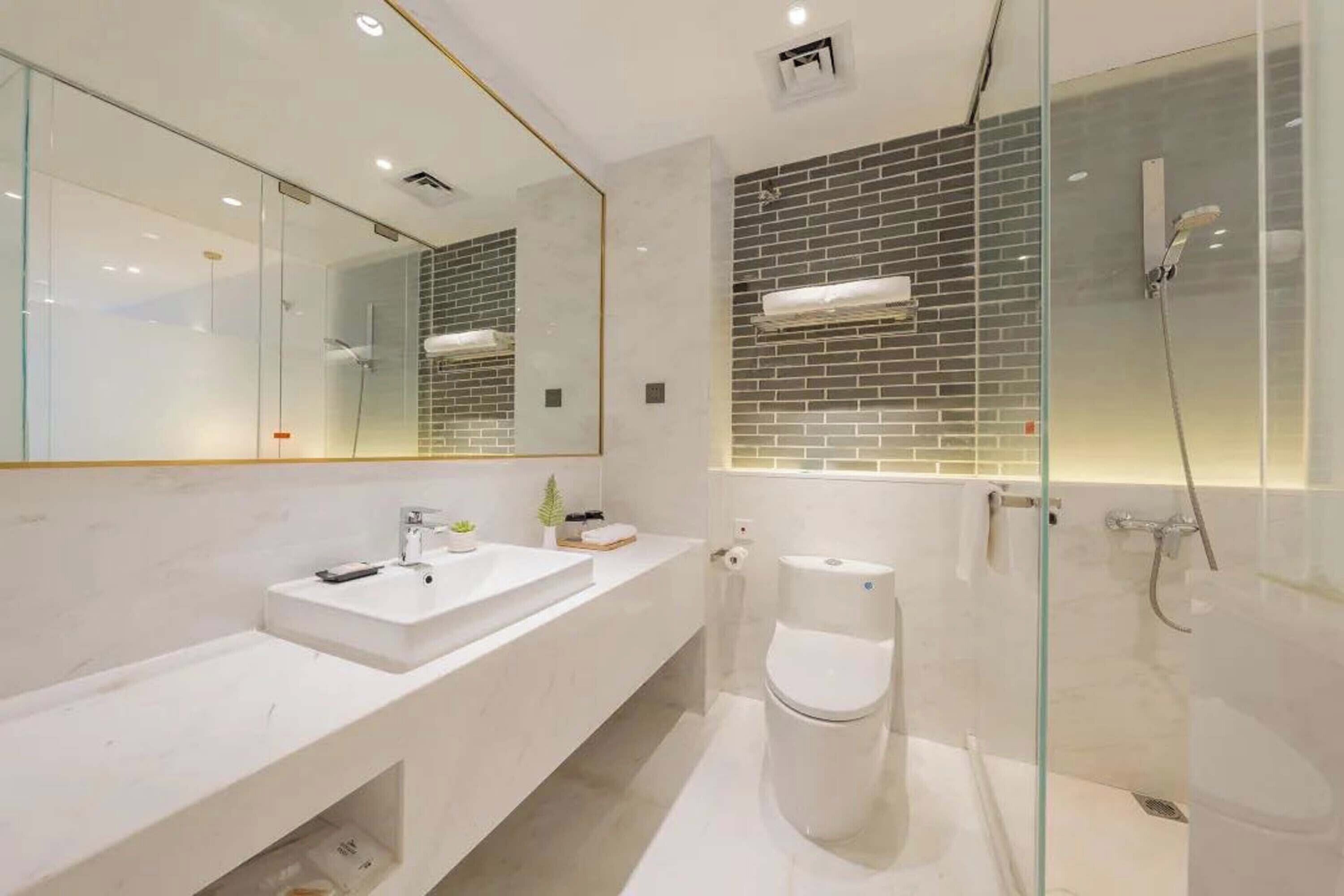 A modern bathroom with a white vanity, a glass shower enclosure, and a tiled shower wall.
