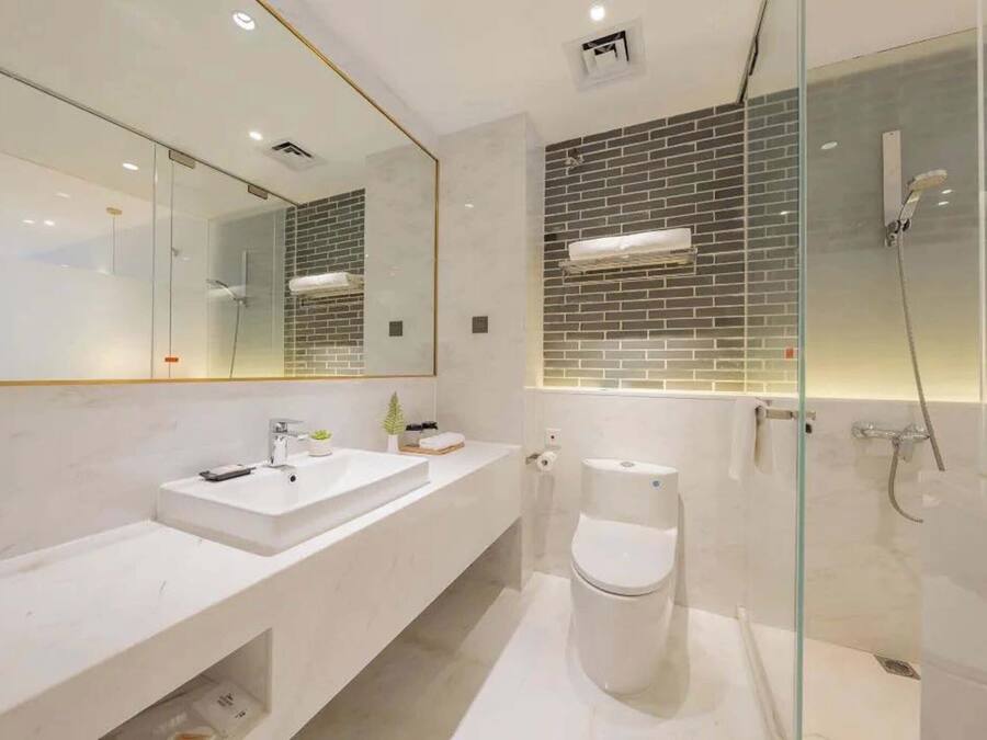 A modern bathroom with a white vanity, a glass shower enclosure, and a tiled shower wall.