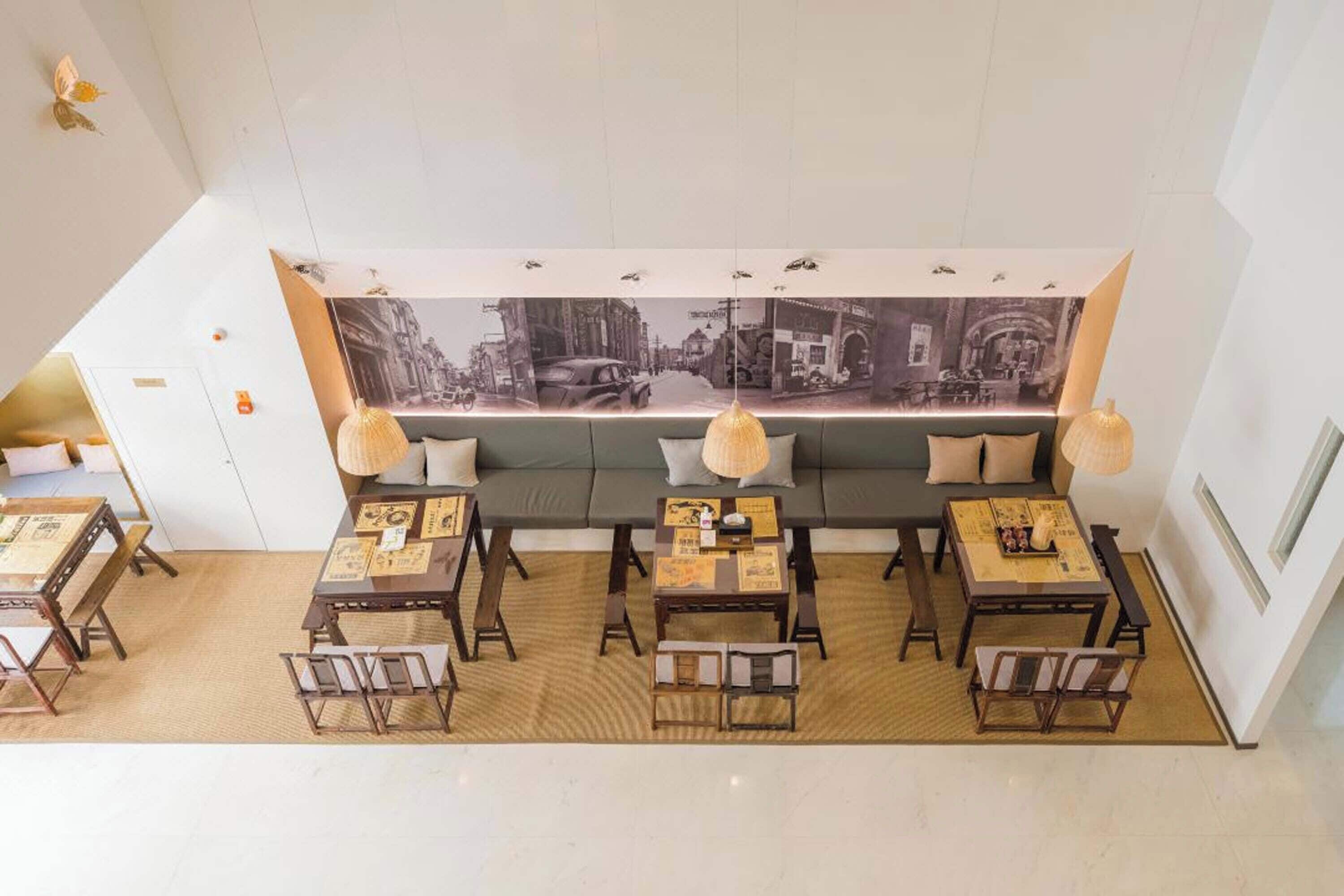 Un restaurant doté d’une longue table conviviale, de tables individuelles et d’une grande fresque murale au fond de la salle.