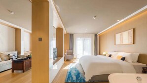A modern hotel room with a large bed, a sitting area with a sofa and armchair, a desk, and a bathroom with a bathtub. - Wangting Jinxiu Hotel (Shanghai)