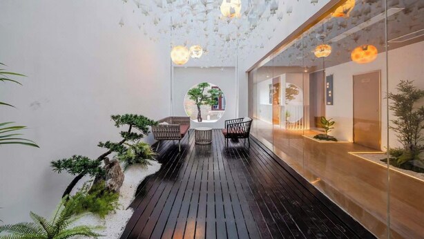 A modern interior with a wooden deck, seating area, and a glass wall with plants. - Wangting Jinxiu Hotel (Shanghai)