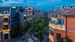 A courtyard with a mix of modern and traditional architecture, featuring a central tree and a patterned pavement. - Wangting Jinxiu Hotel (Shanghai)