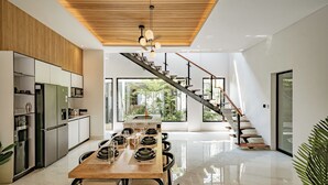 Eine moderne Küche mit Holzboden, ein Essbereich mit Holztisch und -stühlen sowie eine Treppe zu einem Balkon mit Blick auf Grünflächen.