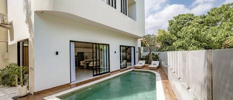 A modern two-story house with a swimming pool, large windows, and a patio area.