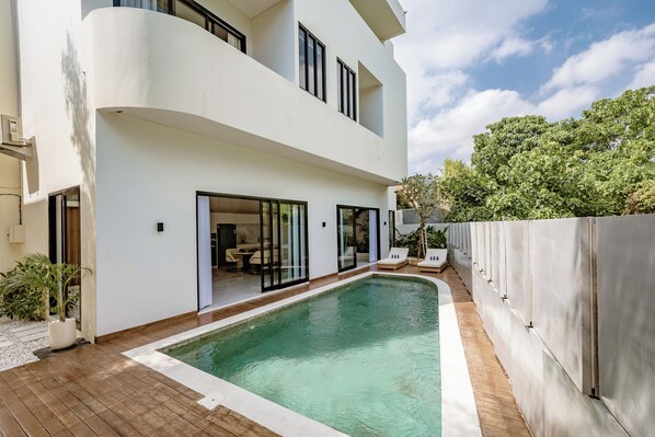 A modern two-story house with a swimming pool, large windows, and a patio area.