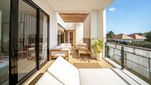 Un balcon avec un canapé, une table et un pot de fleurs.