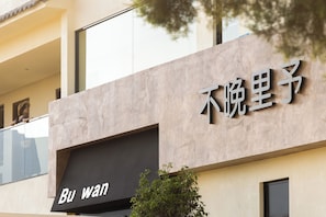 A building with a sign that reads "Bu wan" and another sign with Chinese characters.