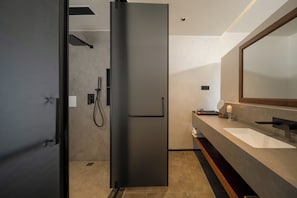 A modern bathroom with a large mirror, a sink, and a shower area.
