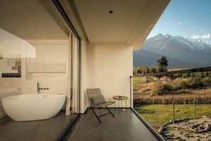 A modern bathroom with a freestanding bathtub, a chair, and a small table.