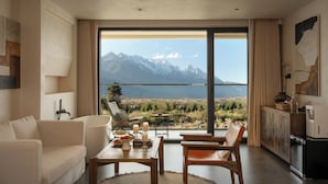 A modern living room with a large sliding glass door leading to a balcony with a mountain view.