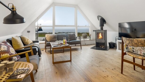 A loft-style room with a large window, a fireplace, a sofa, a coffee table, and a TV.