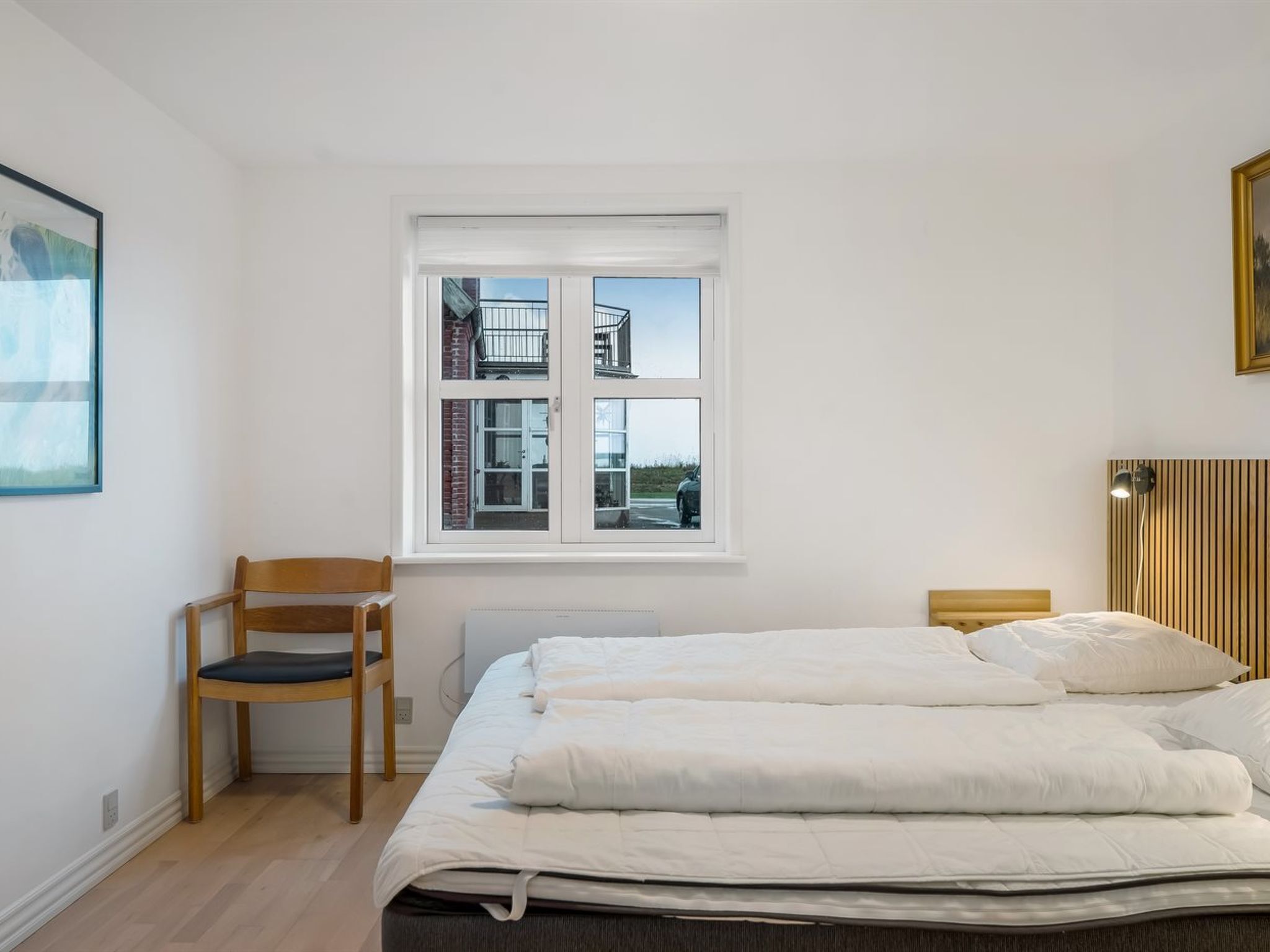 Une chambre à coucher avec un lit, une chaise, une fenêtre et un radiateur.