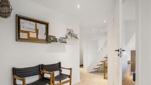 A hallway with two wooden chairs, a framed bulletin board, and a staircase.