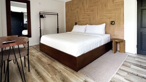 Une chambre moderne avec un grand lit, une tête de lit en bois, une table de chevet, un bureau avec une chaise et un miroir.