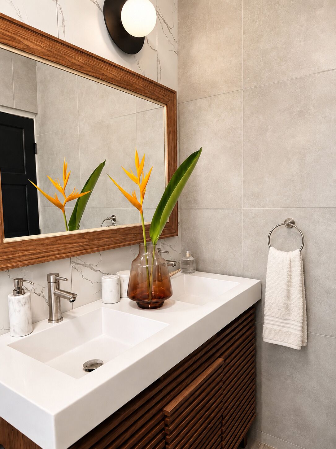 A bathroom with a white sink, a mirror, a towel ring, and a plant.
