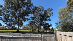 A fenced outdoor area with trees and a clear sky. - Cosy home in Killara (Killara)
