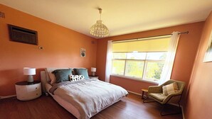 A bedroom with a bed, bedside tables, a chair, a window with curtains, and a ceiling light fixture. - Cosy home in Killara (Killara)