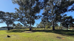 A grassy outdoor area with trees and a fence. - Cosy home in Killara (Killara)