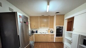 A kitchen with wooden cabinets, a stainless steel refrigerator, a stove, and a microwave. - Cosy home in Killara (Killara)