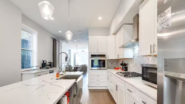 A modern kitchen with white cabinetry, stainless steel appliances, and a marble countertop. - NEW! Stylish 3BD/2.5BTH w/parking! United Center! (Chicago)